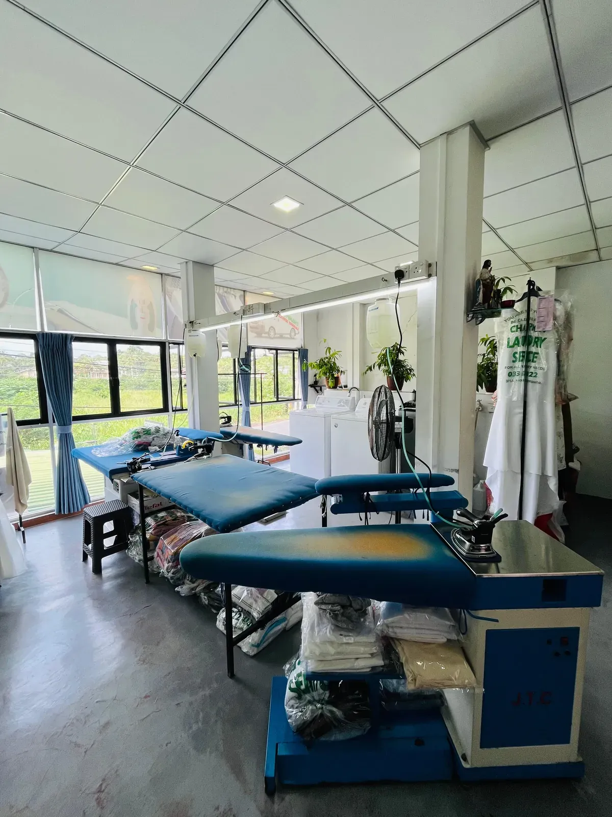 A row of pressing and ironing stations on the Champion Laundry shop floor in Gampaha
